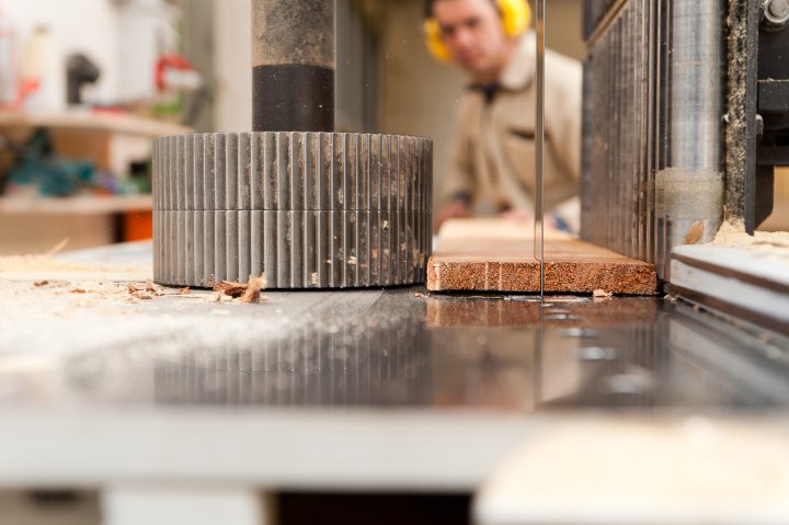 Ein Handwerker beim sägen eines Holzbretts